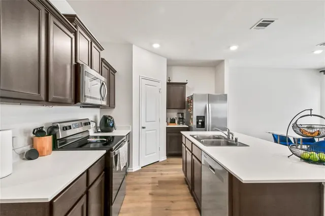 a kitchen with stainless steel appliances granite countertop a sink stove refrigerator and cabinets