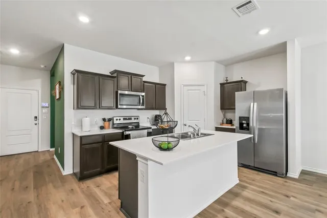a kitchen with stainless steel appliances a stove refrigerator sink and microwave