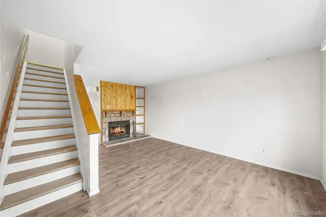 a view of an empty room with wooden floor and stairs
