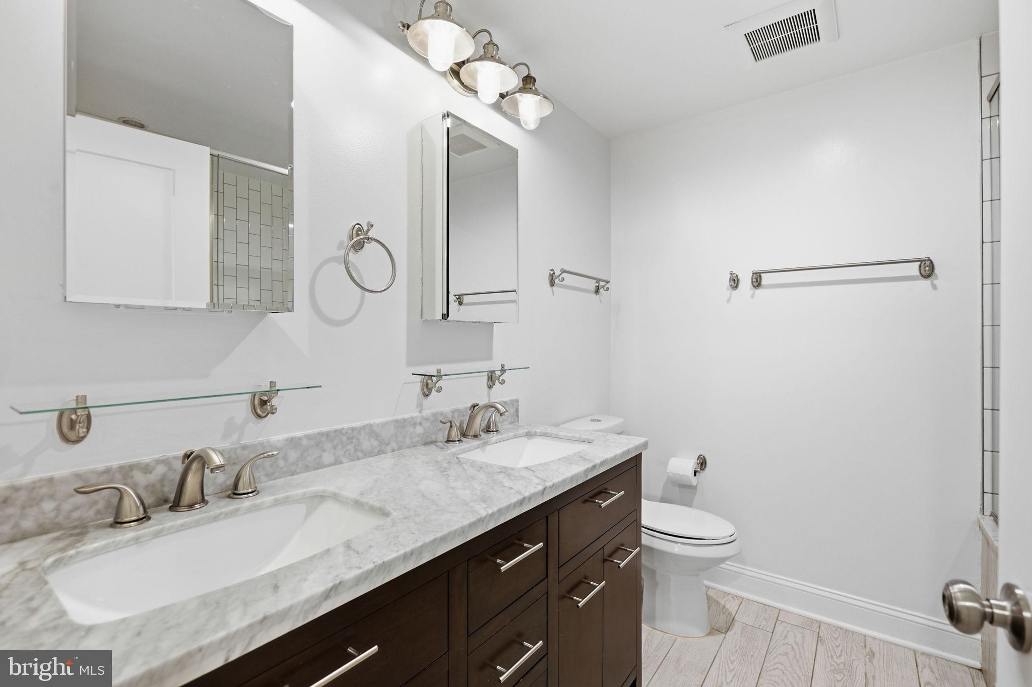 1820 Independence Avenue Southeast, Unit 1 Washington, DC 20003 - Photo 19 of 32 a bathroom with a granite countertop sink a toilet and a mirror