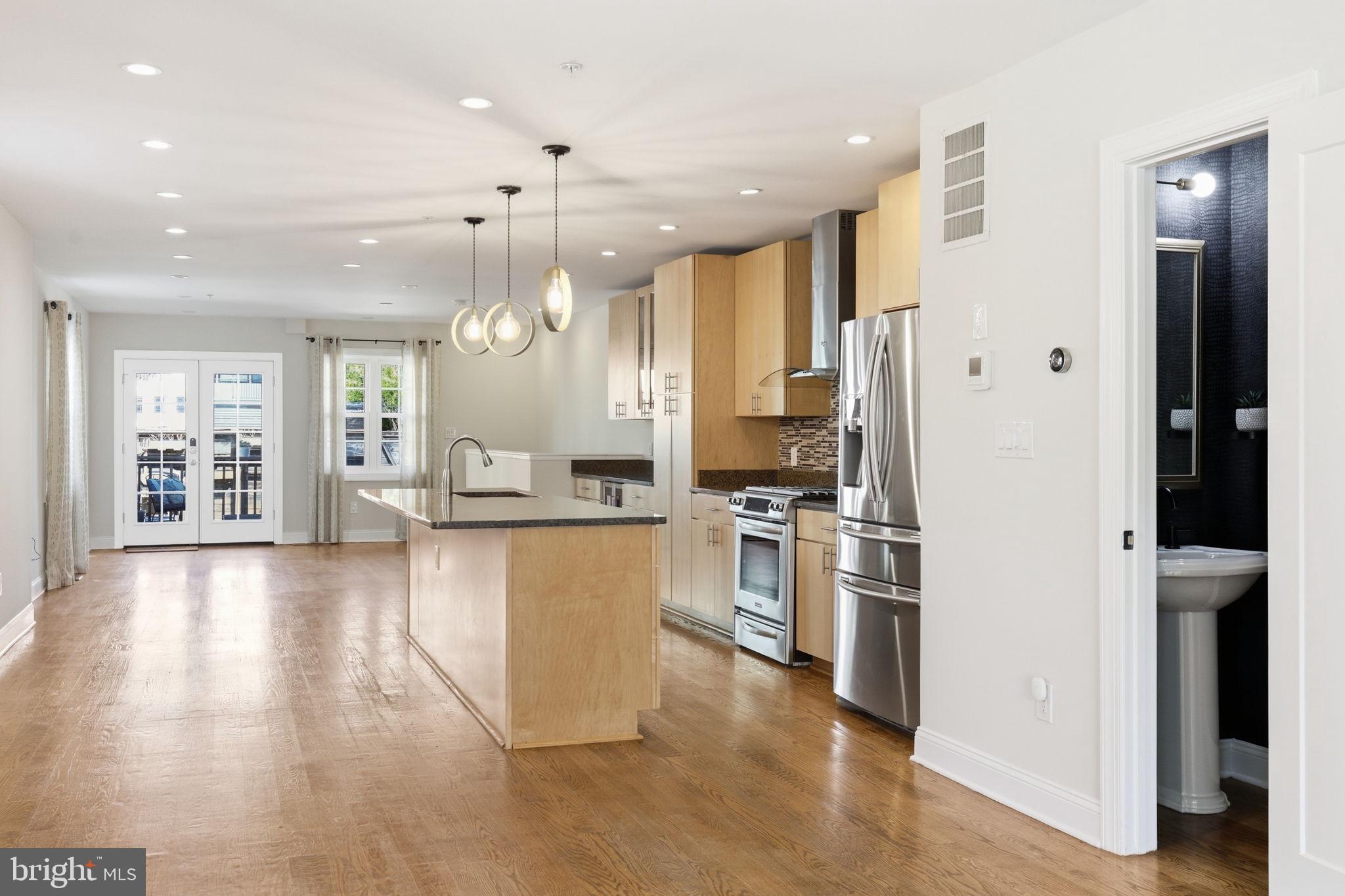1820 Independence Avenue Southeast, Unit 1 Washington, DC 20003 - Photo 4 of 32 a kitchen with stainless steel appliances kitchen island granite countertop a refrigerator oven a sink dishwasher and white cabinets with wooden floor