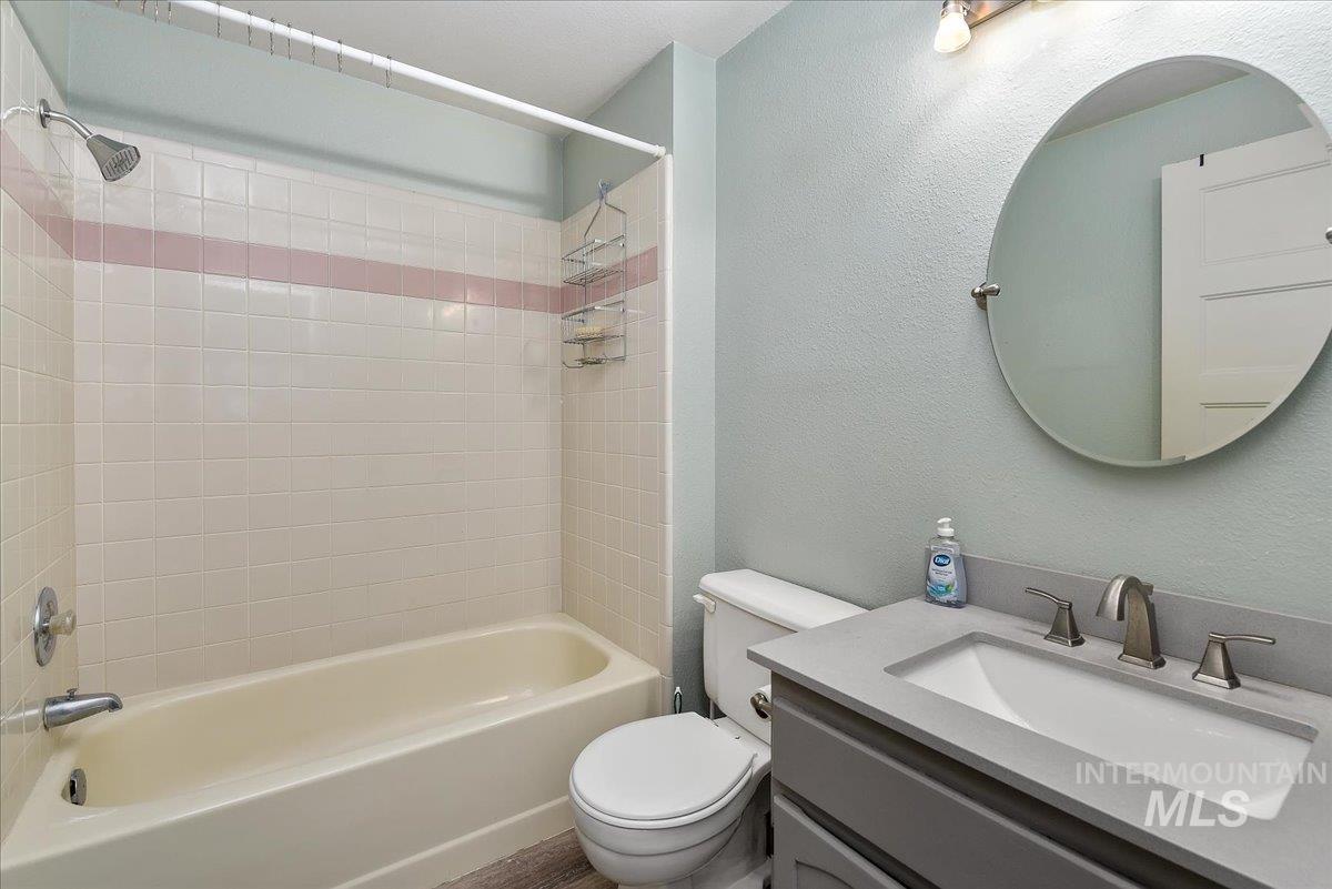 9215 West Preece Street Boise, ID 83704 - Photo 13 of 22 Bathroom featuring a tub and shower combination with light-colored tile surround and an accent stripe