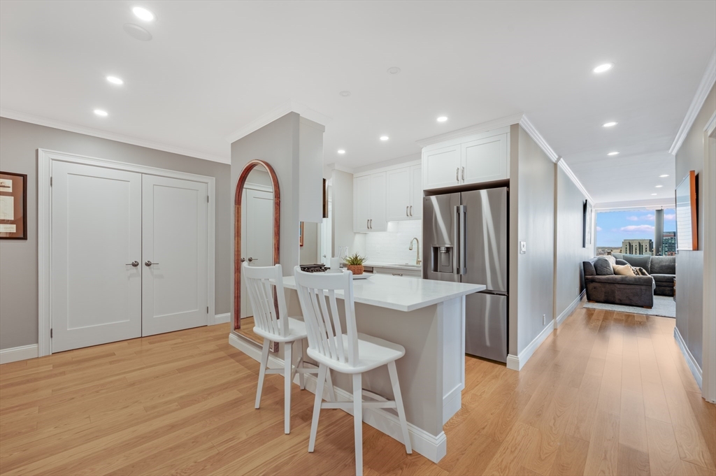 85 East India Row, Unit 34G Boston, MA 02110 - Photo 1 of 20 a kitchen with stainless steel appliances granite countertop a refrigerator a stove a sink dishwasher and white cabinets with wooden floor