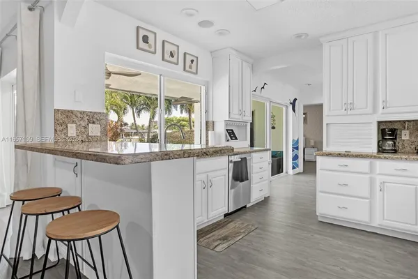 a kitchen with stainless steel appliances kitchen island wooden floors and white cabinets