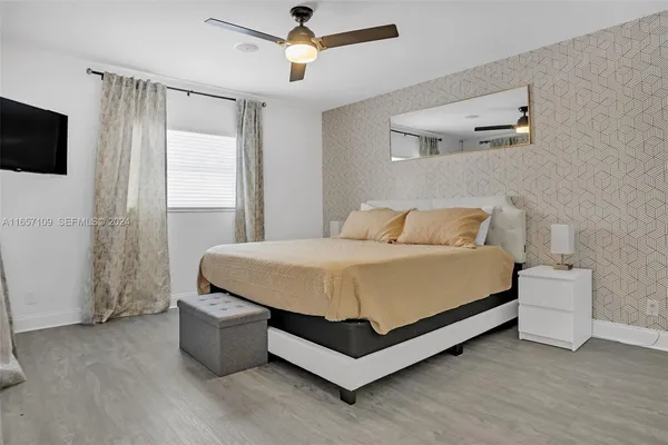 a spacious bedroom with a bed and a flat tv screen