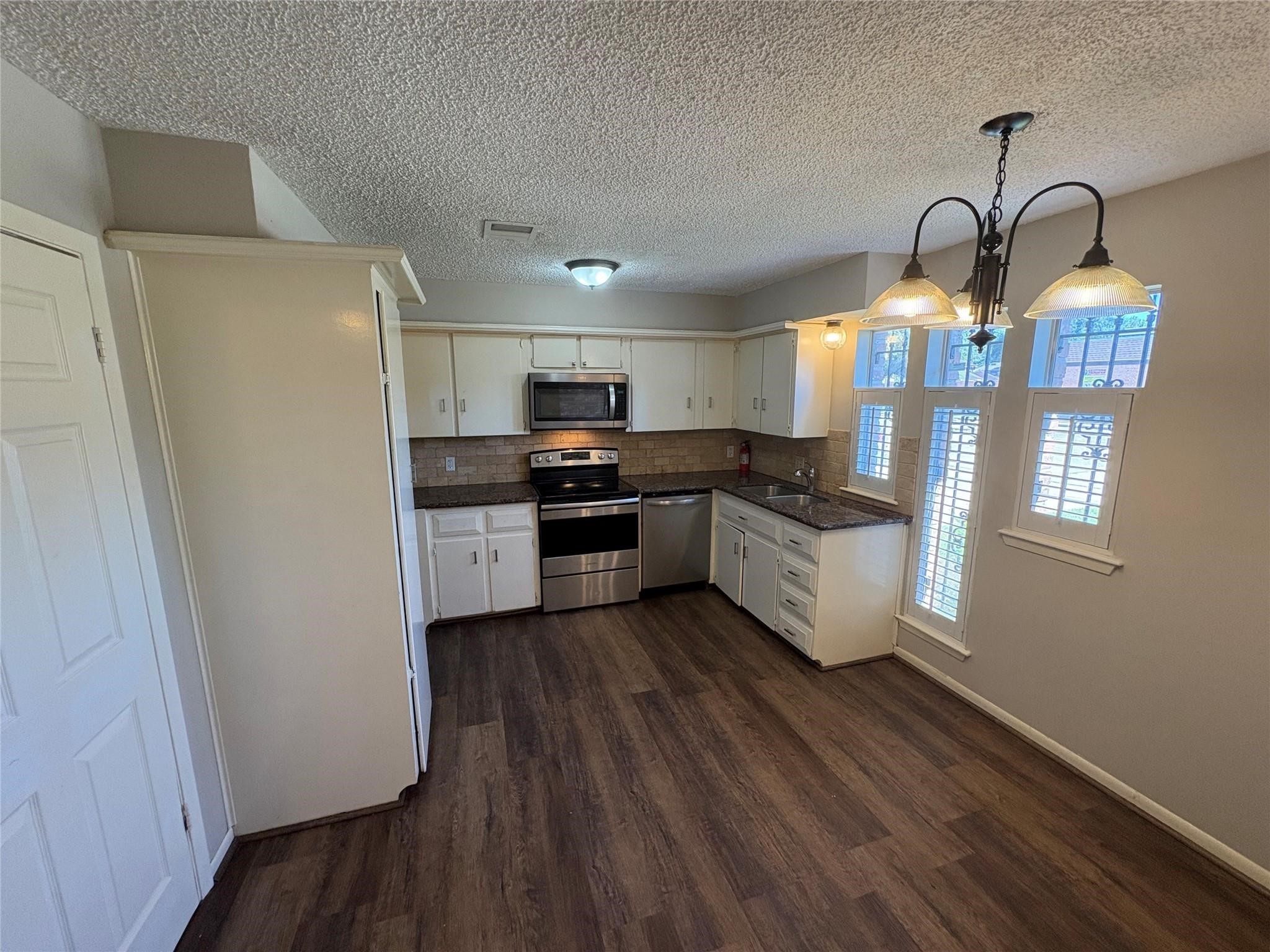 17159 Beaver Springs Drive, Unit 13 Houston, TX 77090 - Photo 4 of 14 a kitchen with stainless steel appliances a refrigerator a stove a sink dishwasher and white cabinets with wooden floor