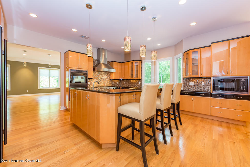 500 Farm Bridge Road Marlboro, NJ 07746 - Photo 16 of 57 a kitchen with stainless steel appliances granite countertop a stove a refrigerator a kitchen island with a stove and white cabinets