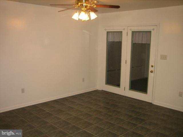 1213 Krueger Avenue Rosedale, MD 21237 - Photo 9 of 27 an empty room with a chandelier fan and windows