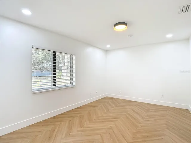 a view of an empty room with wooden floor and a window