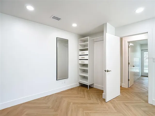 a view of a hallway with wooden floor and a kitchen