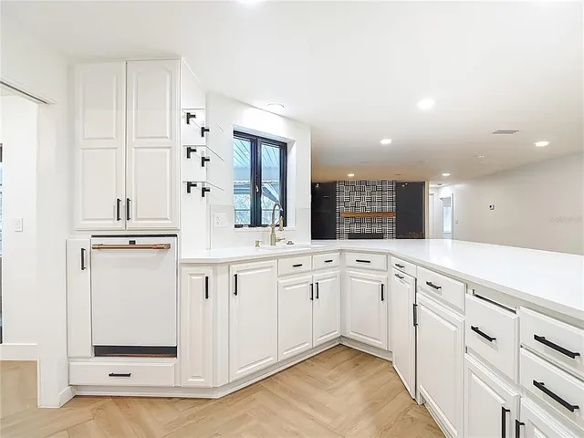 a view of a kitchen with kitchen island a sink wooden floor and a refrigerator