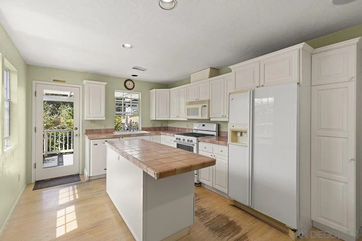 5532 Bellevue Avenue La Jolla, CA 92037 - Photo 11 of 26 a kitchen with stainless steel appliances granite countertop a refrigerator a sink a stove and white cabinets with wooden floor