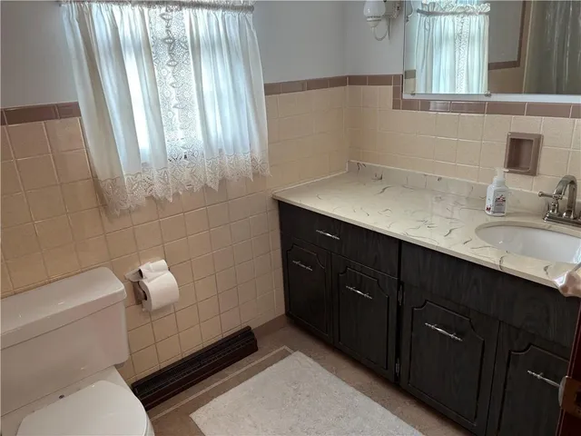 a bathroom with a granite countertop sink a toilet and mirror