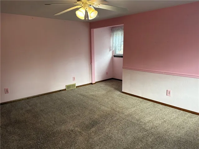 an empty room with a chandelier fan and windows