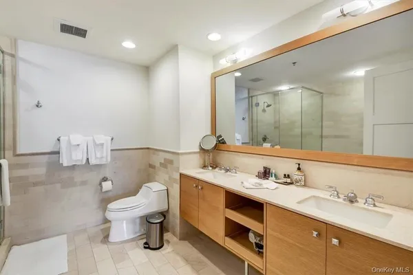 a bathroom with a granite countertop double vanity sink a mirror and toilet
