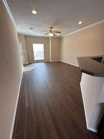 a view of an empty room with wooden floor and chandelier fan