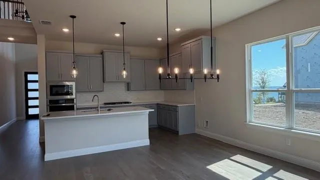 a large kitchen with kitchen island a sink stainless steel appliances and a chandelier
