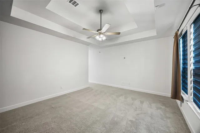 an empty room with a chandelier fan and windows