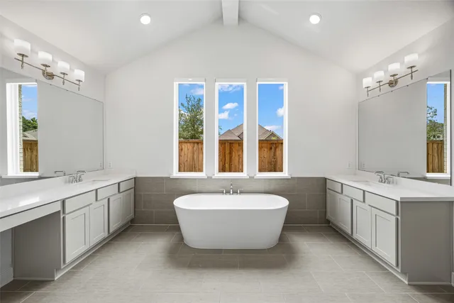 a spacious bathroom with a tub double sink and mirror
