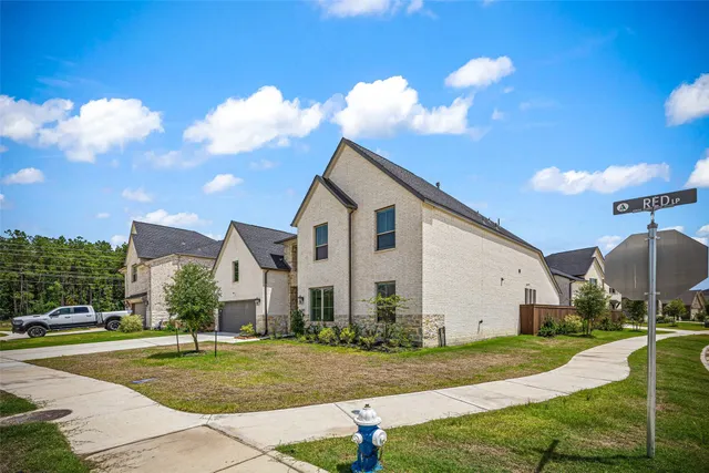 a view of a white house next to a yard with big trees