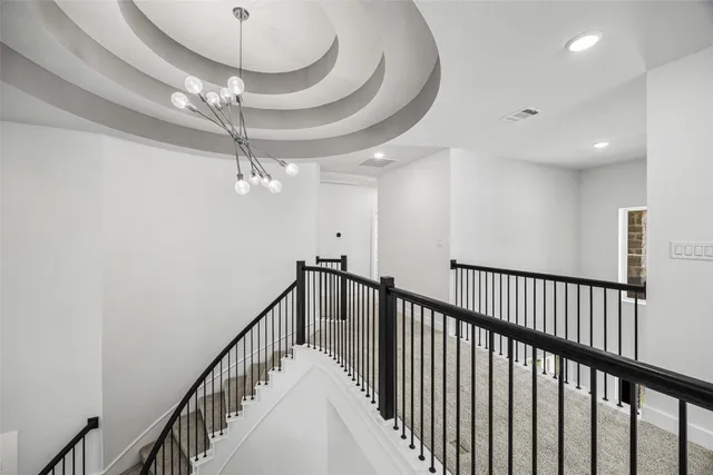 a view of staircase with railing and chandelier