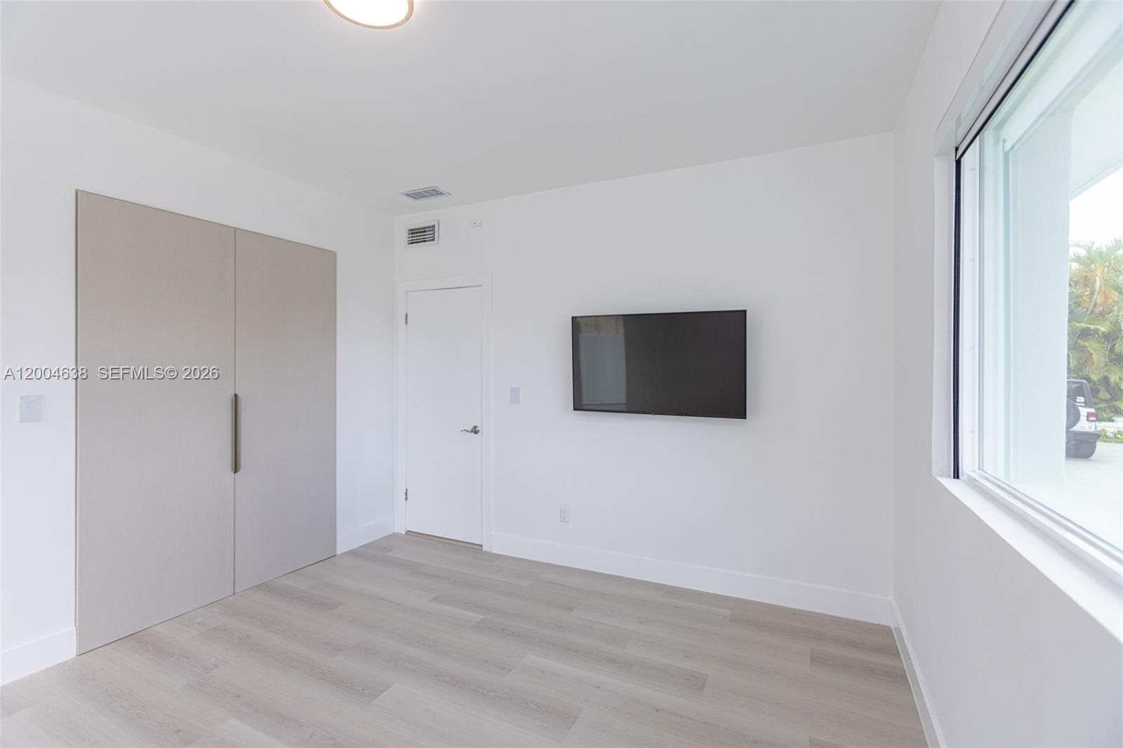 1690 Daytonia Road Miami Beach, FL 33141 - Photo 41 of 88 a view of an empty room with wooden floor and a window