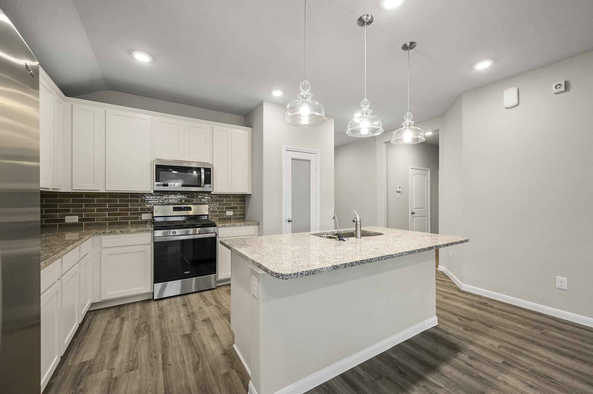 4507 Frontier Trail Baytown, TX 77521 - Photo 7 of 24 a kitchen with a sink dishwasher a stove top oven a kitchen island with wooden floor and cabinets