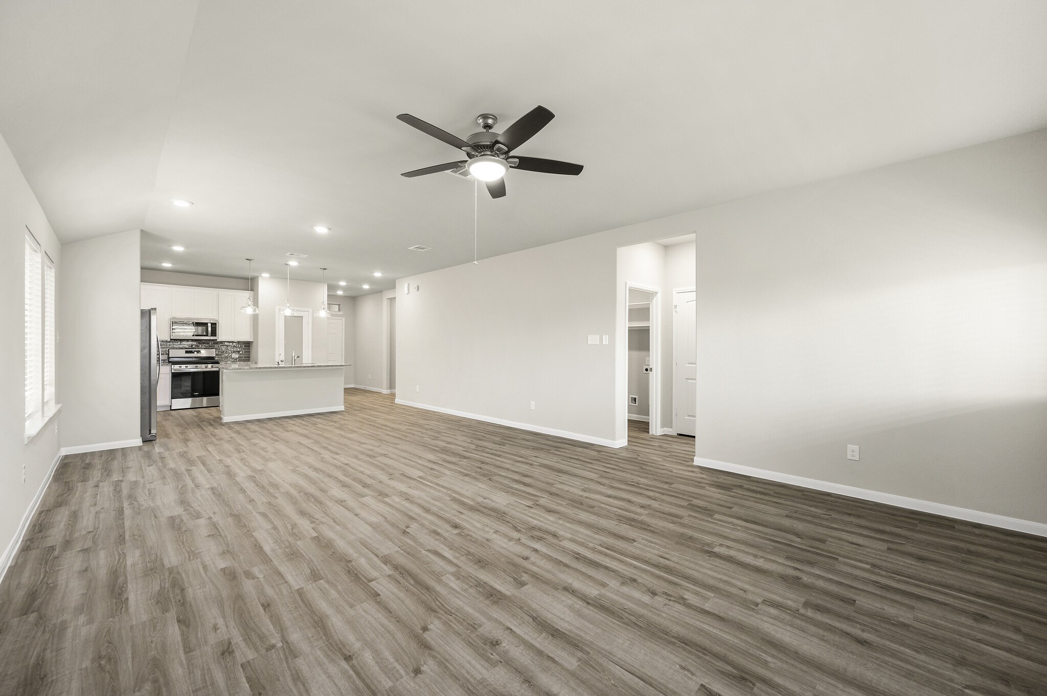 4507 Frontier Trail Baytown, TX 77521 - Photo 10 of 24 a view of an empty room with wooden floor a ceiling fan and windows