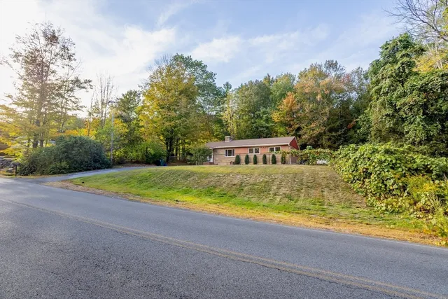 a view of pool house with yard and trees in the background