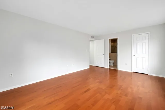 a view of an empty room with wooden floor and window