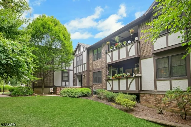 a view of a brick house with a yard and plants