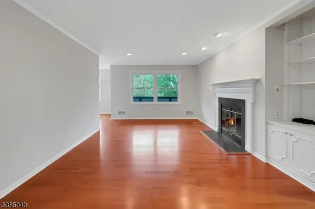 an empty room with wooden floor fireplace and windows