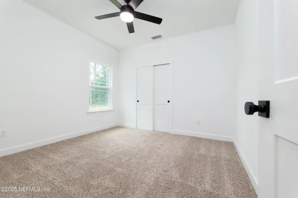 an empty room with windows and fan view
