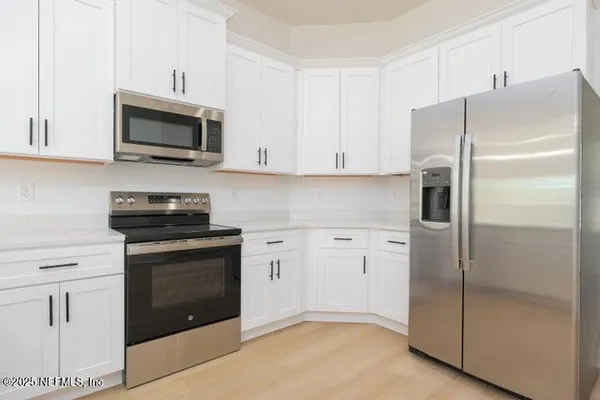 a kitchen with white cabinets and stainless steel appliances