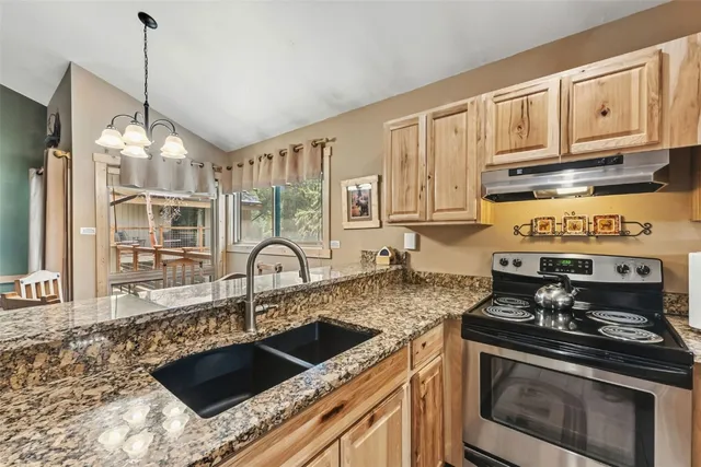 a kitchen with granite countertop a stove a sink and cabinets