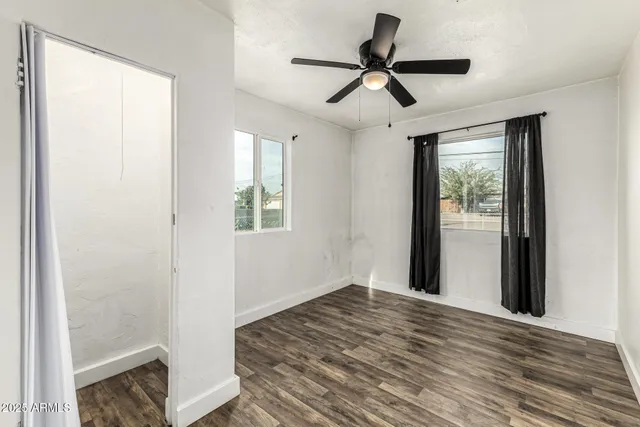 a view of empty room with wooden floor and fan