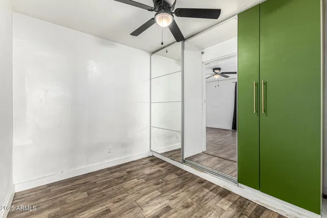 a view of empty room with wooden floor and fan