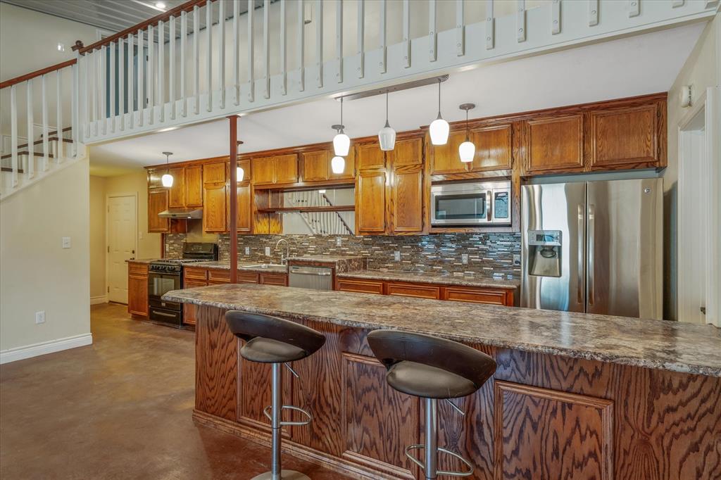 1070 Piney Grove Road Rusk, TX 75785 - Photo 12 of 39 Kitchen featuring wood finish cabinets, stainless steel appliances, a breakfast bar area, finished concrete flooring, and dark stone counters