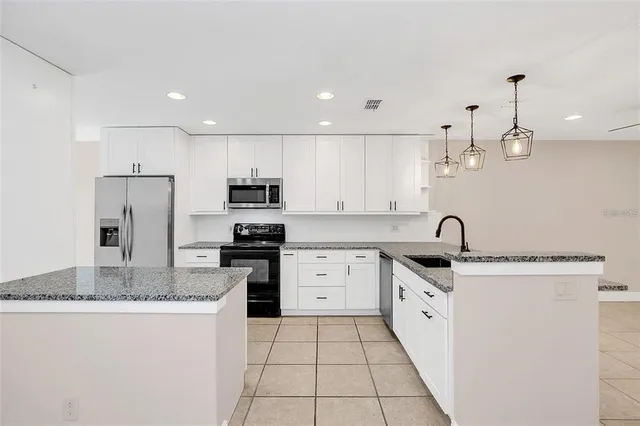 a kitchen with stainless steel appliances granite countertop a sink a stove a refrigerator and a refrigerator