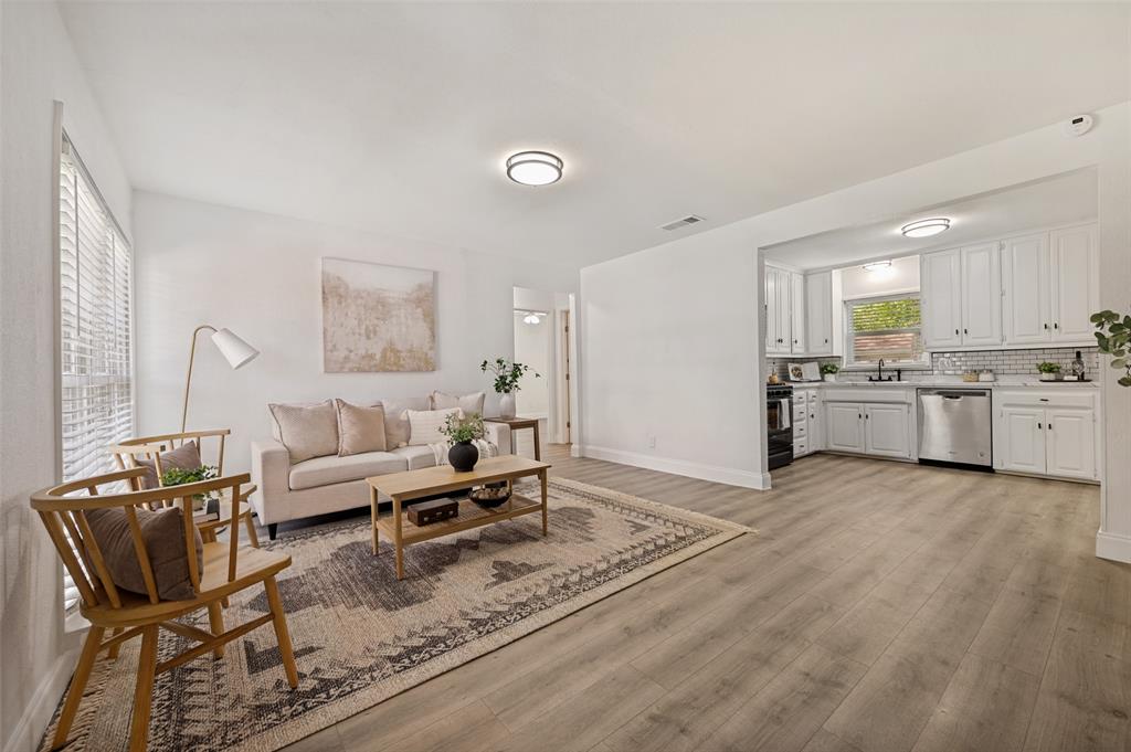 2316 Cunningham Street Irving, TX 75062 - Photo 6 of 22 Open-concept living area featuring light wood-finish flooring, white walls, recessed lighting, and a kitchen with white cabinetry, stainless steel appliances, and a tiled backsplash