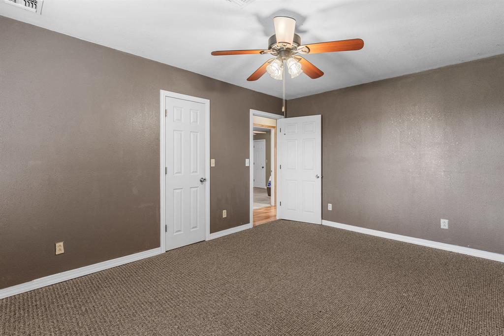 13315 Highway 281 Scotland, TX 76379 - Photo 25 of 40 Spacious 4th bedroom featuring neutral carpeting, a ceiling fan with integrated lighting, two paneled doors, and painted walls