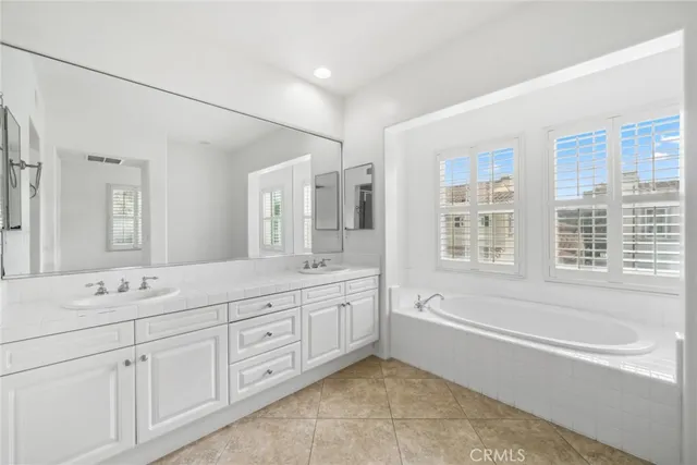 a spacious bathroom with a double vanity sink a mirror and a bathtub