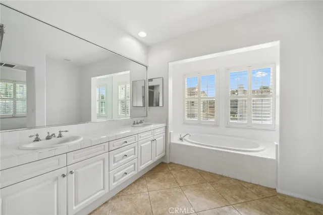 a bathroom with a granite countertop sink mirror bathtub and double