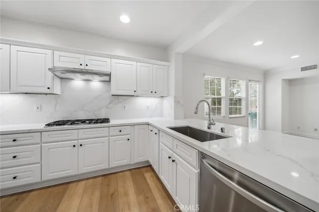 a white kitchen with sink and cabinets
