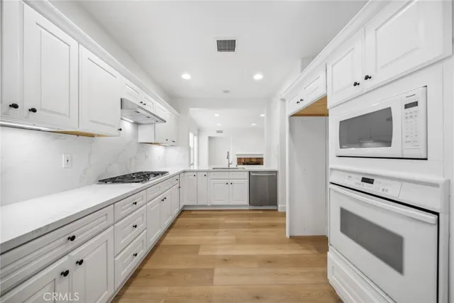 a large kitchen with stainless steel appliances granite countertop a stove a sink and a microwave