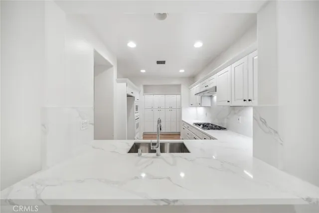 a large white kitchen with kitchen island a stove a sink and a refrigerator