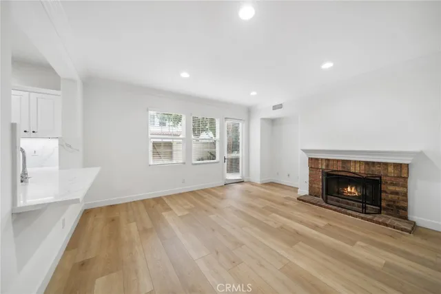 a view of an empty room with wooden floor fireplace and a window