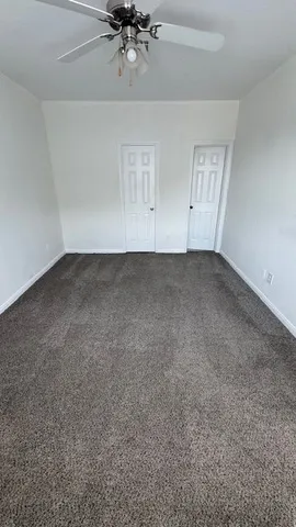 a view of an empty room with a chandelier fan