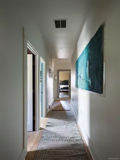 a view of a hallway to a livingroom with wooden floor and furniture