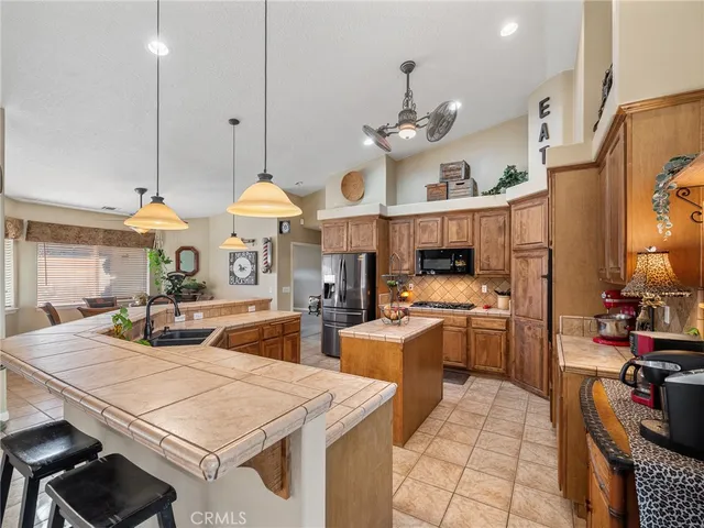 a kitchen with stainless steel appliances granite countertop a stove a sink a oven a dining table and chairs with white cabinets